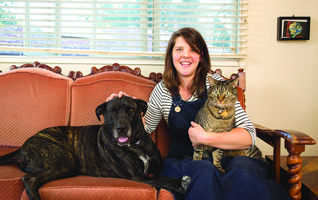 woman sitting on couch with a dog and a cat